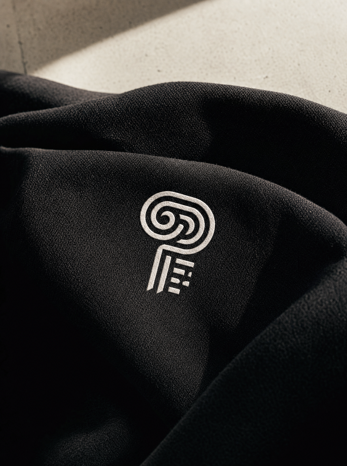Polocom Plus white emblem on black fabric, Still Rising collection campaign.