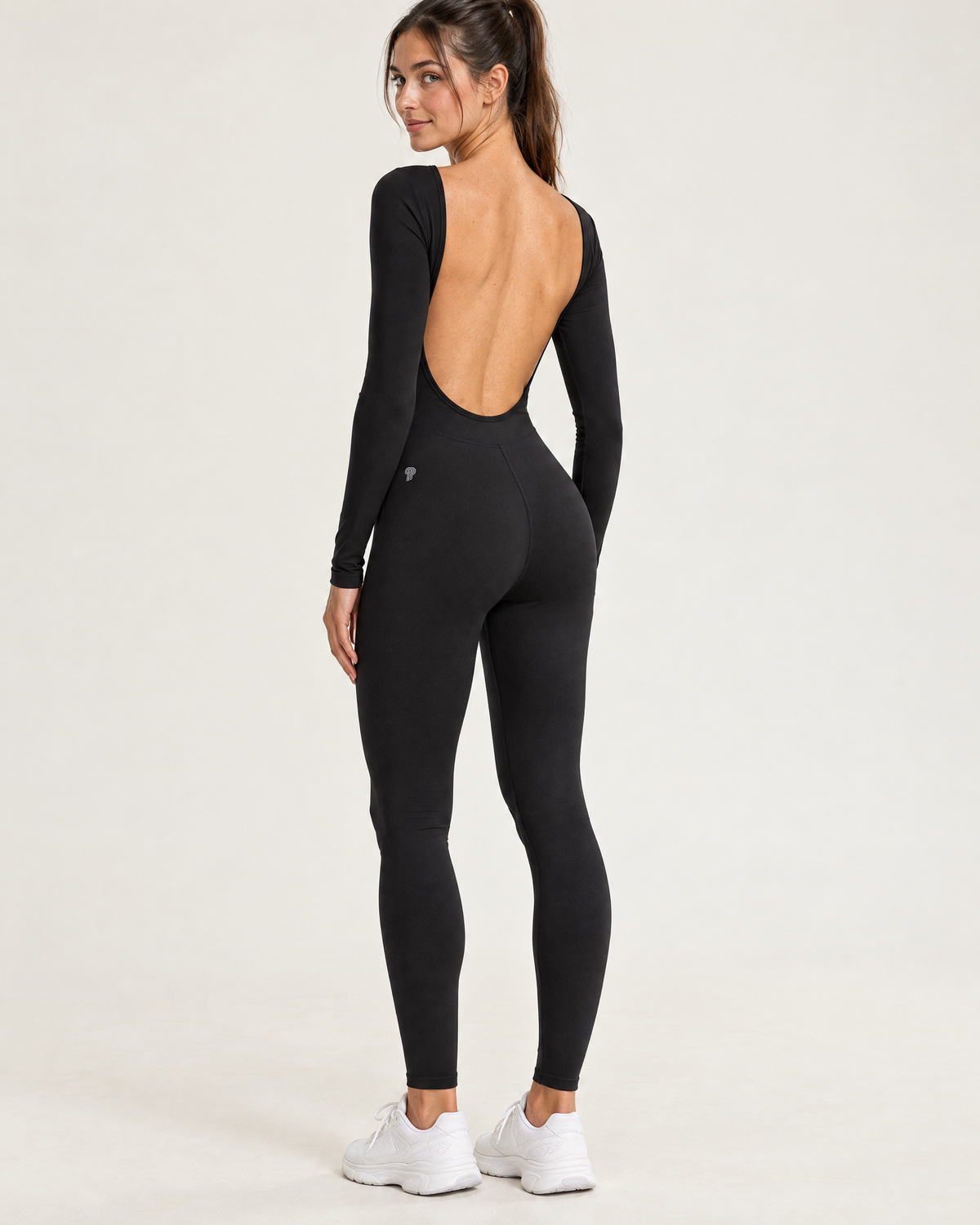 Polocom Plus Arc Open-Back Long-Sleeve Jumpsuit in Black, worn by an adult model with a small silver P emblem