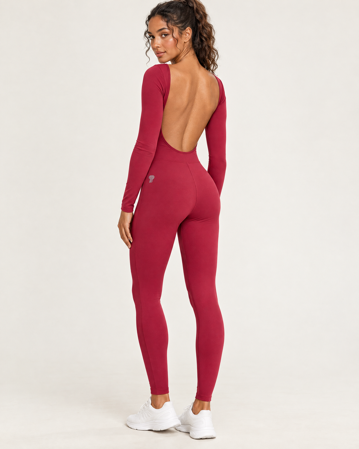 Polocom Plus Arc Open-Back Long-Sleeve Jumpsuit in Cherry Red, worn by an adult model with a small silver P emblem
