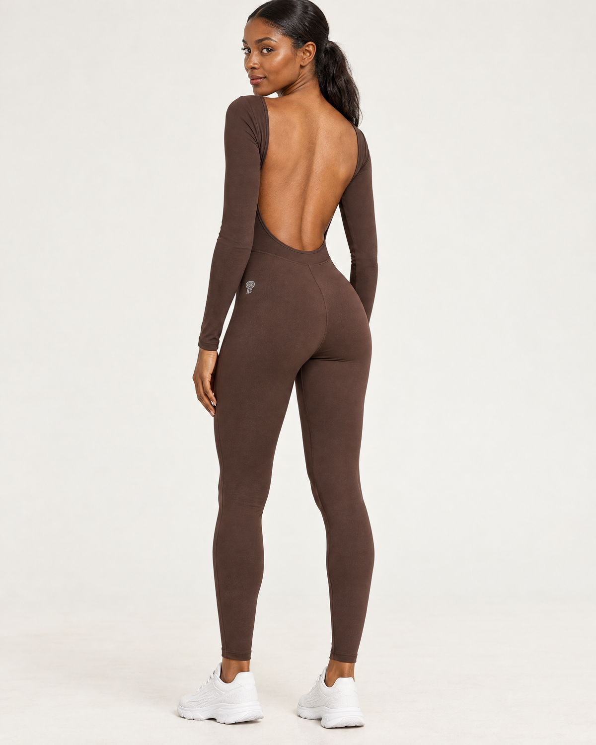 Polocom Plus Arc Open-Back Long-Sleeve Jumpsuit in Dark Brown, worn by an adult model with a small silver P emblem