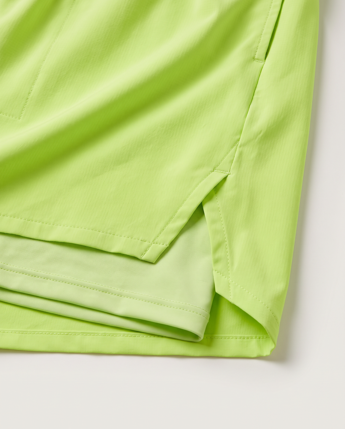 Velocity green running shorts, outer-shell overlap and tonal short-liner detail