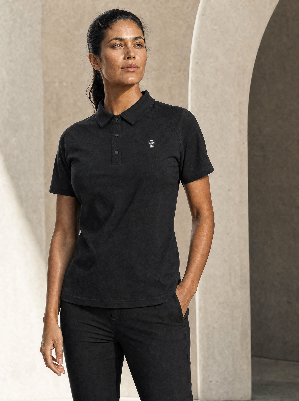 Black Polocom Plus three-button performance polo worn by an adult woman.